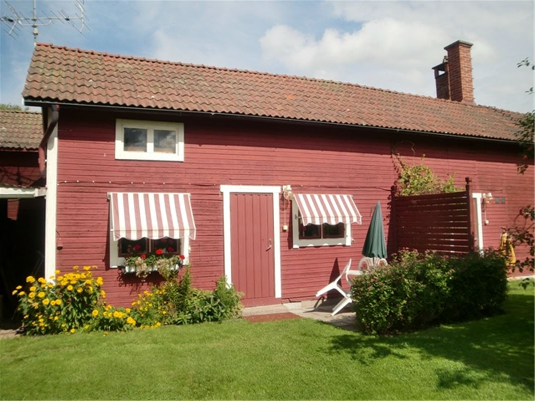 Red house with white linings and red and white striped awnings above the windows. 