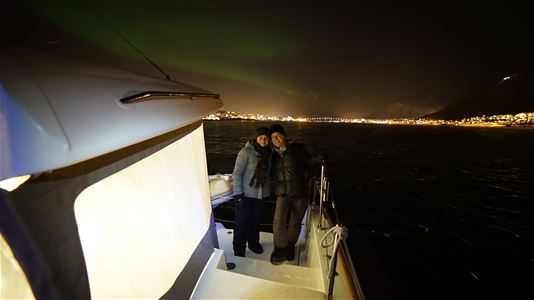 Guests on sailboat with northern lights in the background