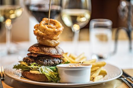 Hamburgare med lökringar och pommes frites.