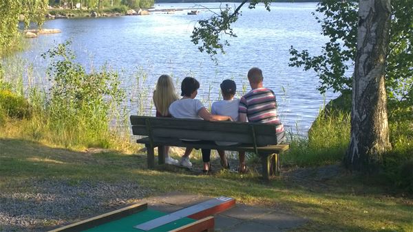Familj på bänk vid sjön 