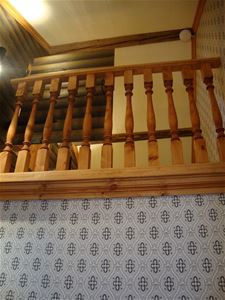 Detail from the wooden stair railing and a patterned wall-paper below. 