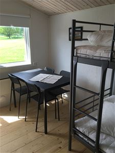 Interior image from a cottage, table, four chairs and a bunk bed.