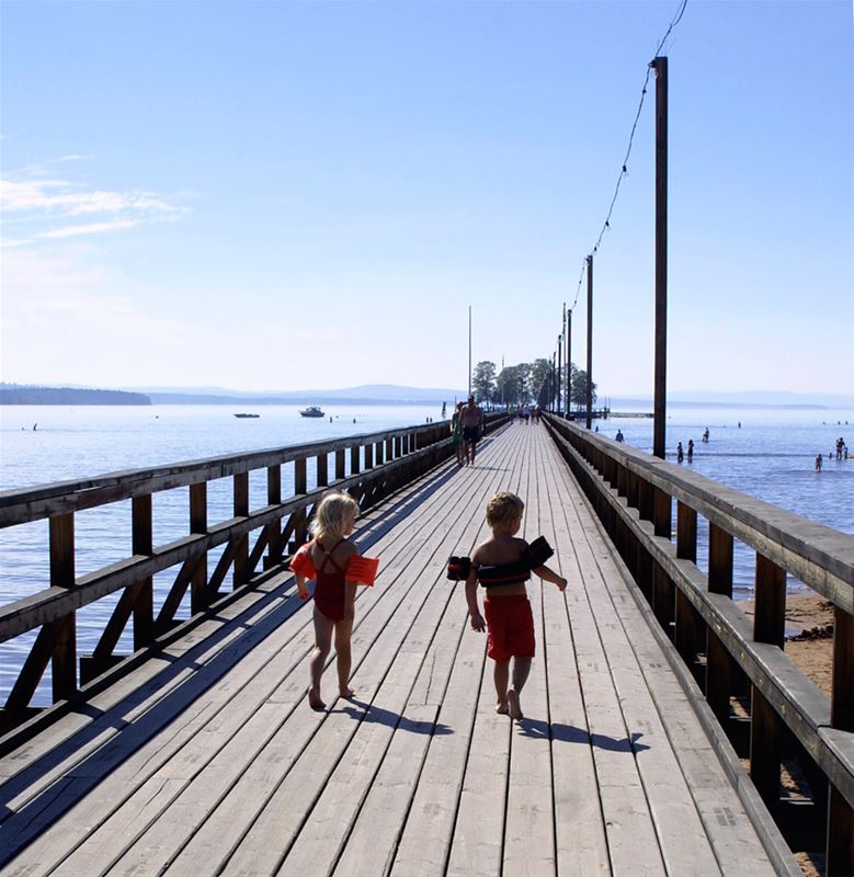 Två barn springer på bryggan.