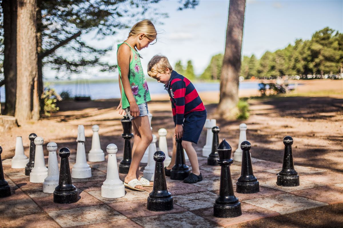 Barn spelar schack utomhus.