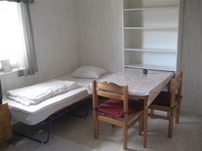 Single bed close to window and a table at the side.