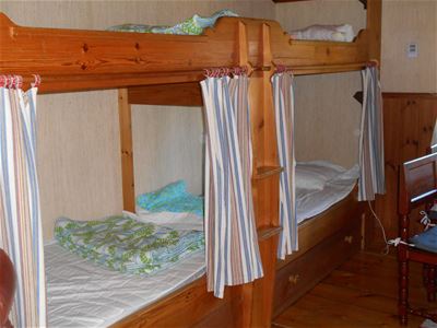 Two wooden bunkbeds with curtains. 