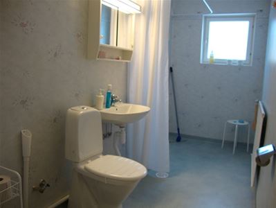 Toalettrum med toalettstol, handfat och dusch.