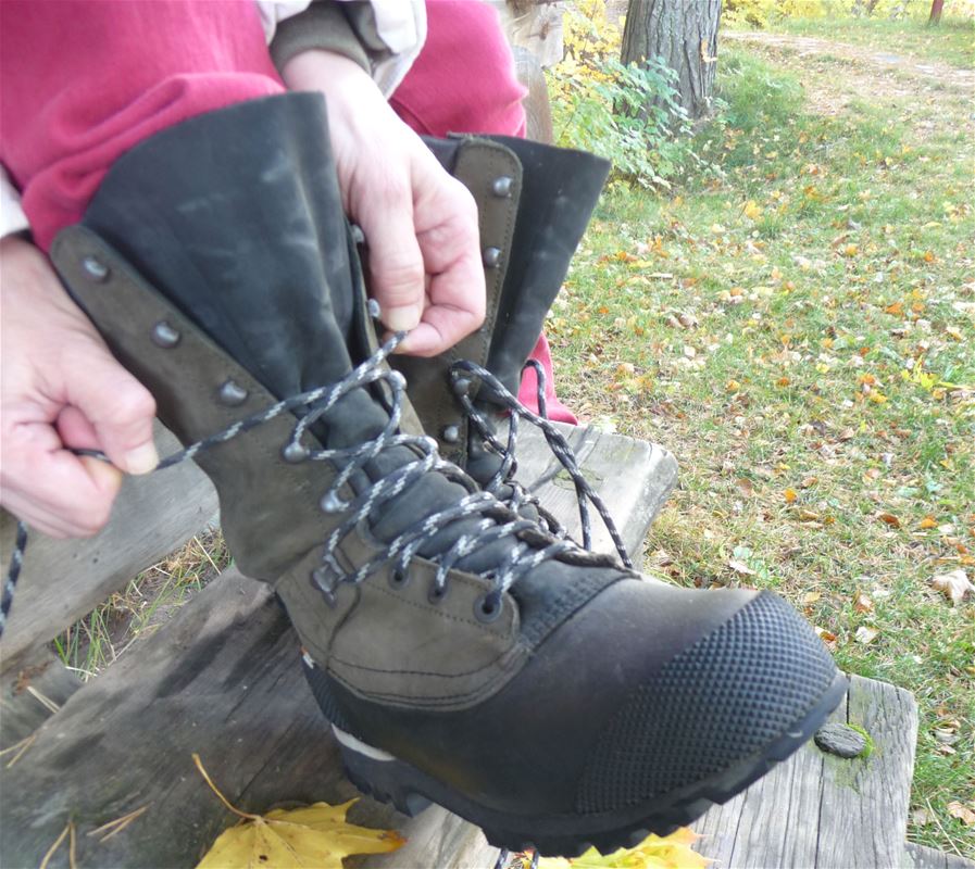 A person tying laces of a hiking boot.