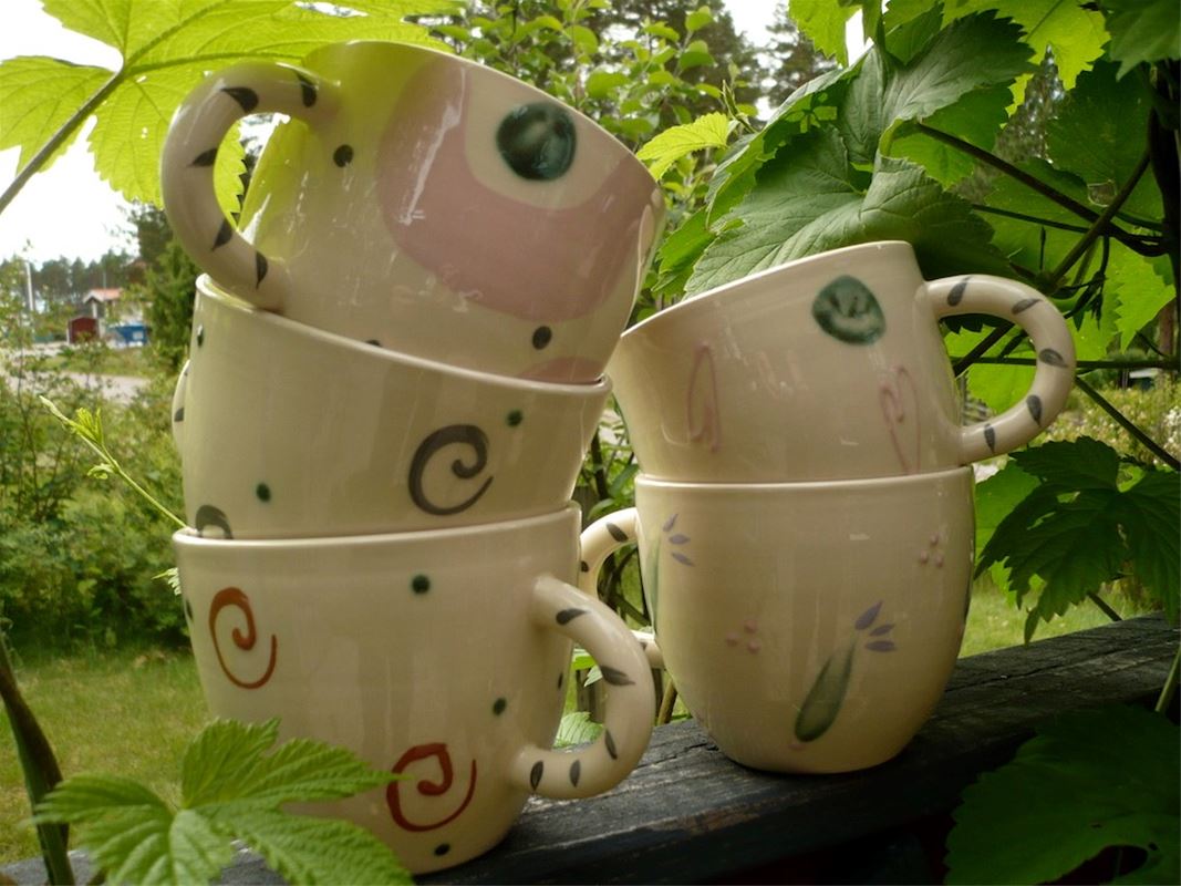 Five white glazed ceramic mugs stacked on top of each other.
