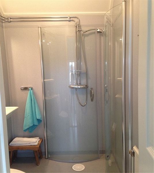 Badrum med duschkabin med glasdörrar. 