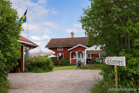 Rött hus med vita knutar, vita parasoller, skylt välkommen.