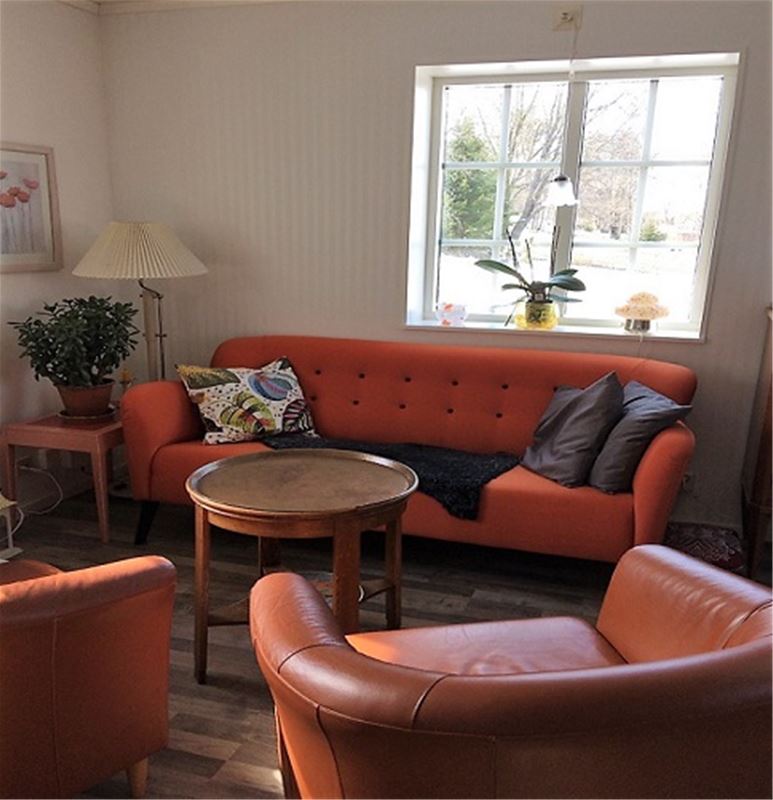 Orange sofa with two llightbrown armchairs in leather around a small, round table. 