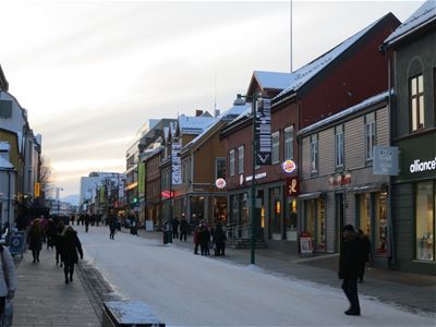 Snow-covered town street with people and shops.