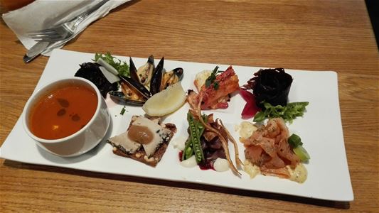 Seafood and soup starter on a white plate.
