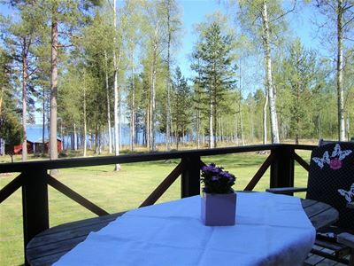 Altan med utemöbler och sjön Siljan som syns mellan björkarna.och s