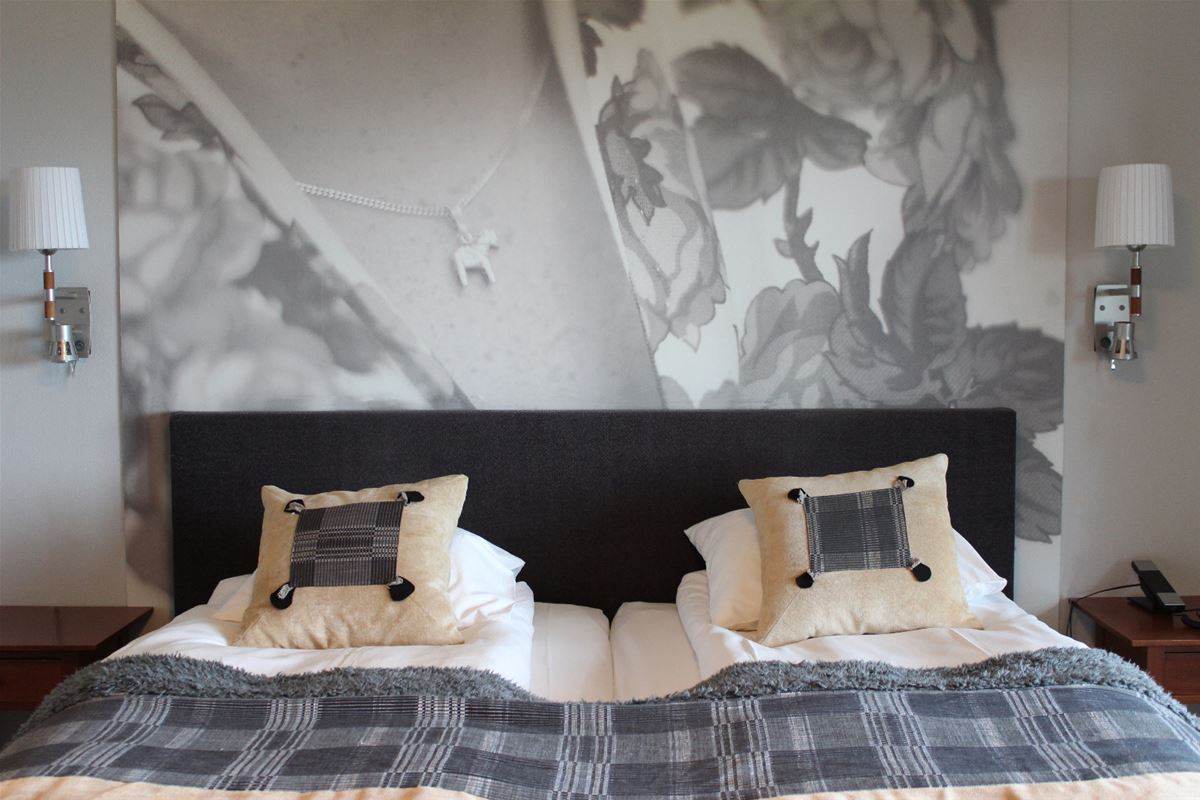 Double bed with blach bed frame and grey-checkered bedspread.