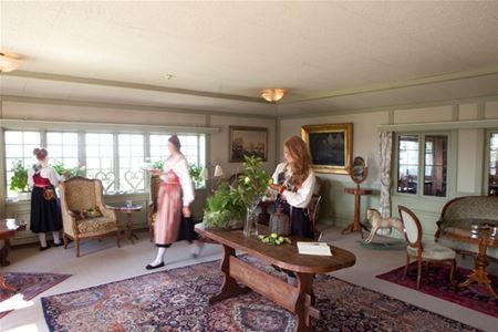 Three women moving in a lounge with large windows and antique furniture