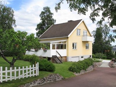 Yellow two-storey house with white terrace with roof