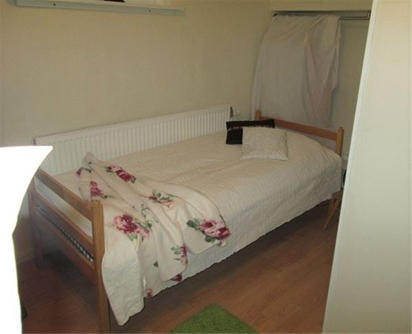 Single bed in a wooden fram and a white bedspread.  