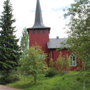 Red wooden chapel behind the trees.