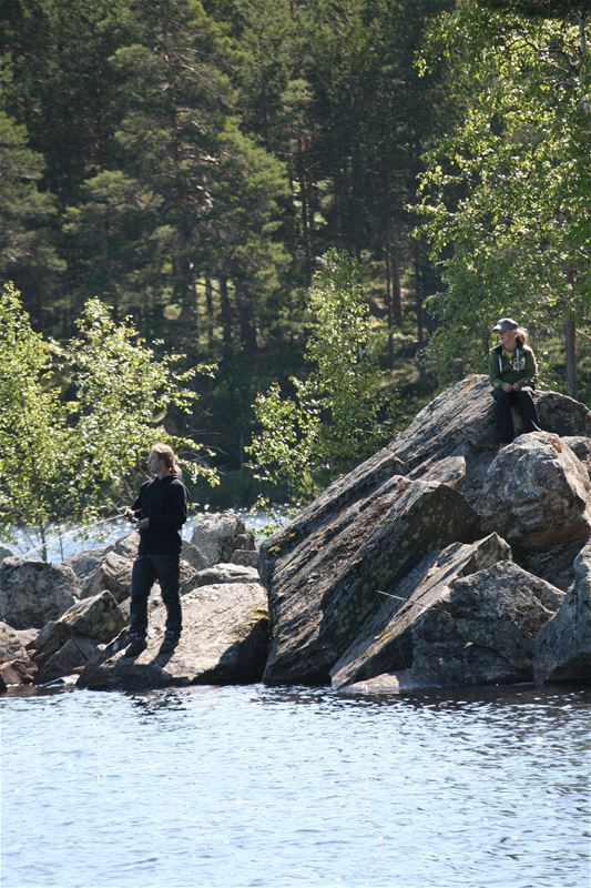 Fiskare på klippblock ute i vattnet.