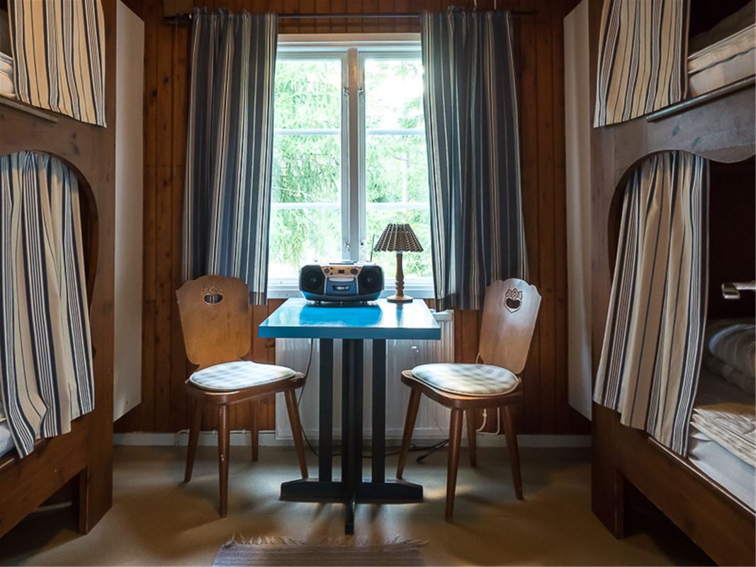 Rum med två våningssängar och ett bord med två stolar.