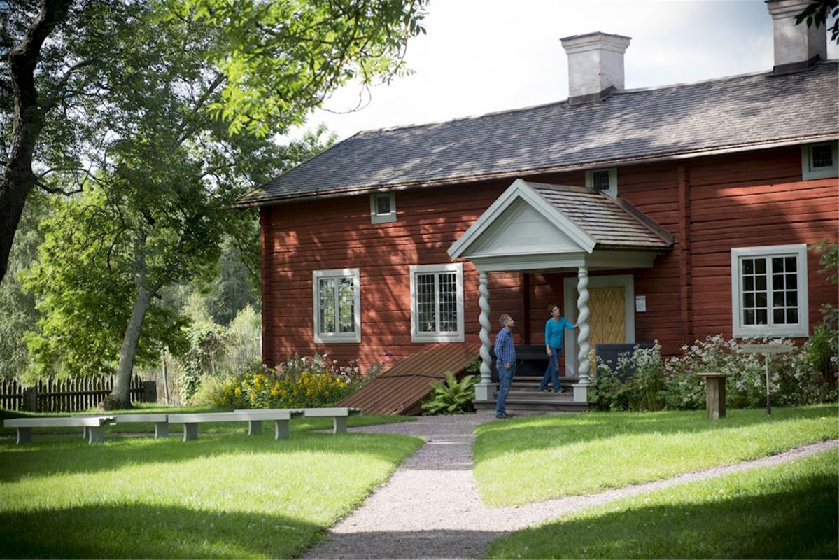 Gravel walks, green benches and Linnes wedding cottage a red building with a porch.