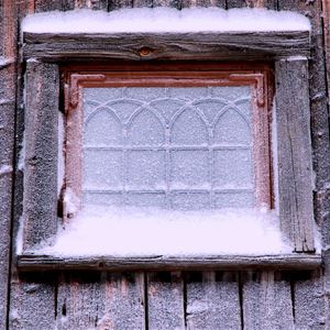 Blyinfattat förnster som har frost på rutan och snö på fönsterbläcket. 