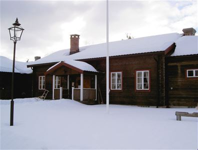 Log cabin with snow on the roof.