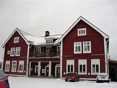 Stort rött tvåvåningshus med vita knutar.