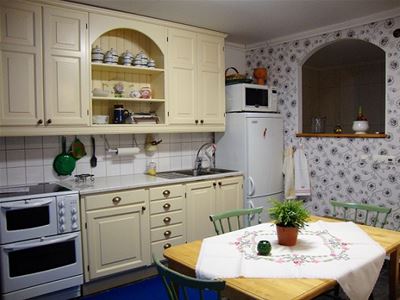 Kitchen with cupboards i soft yellow and dining table. 