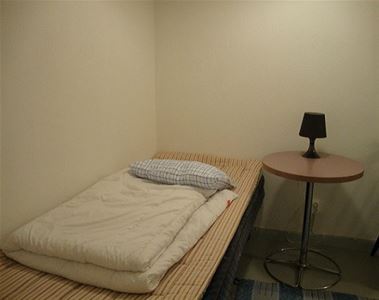 Rum med enkelsäng och ett sängbord.
