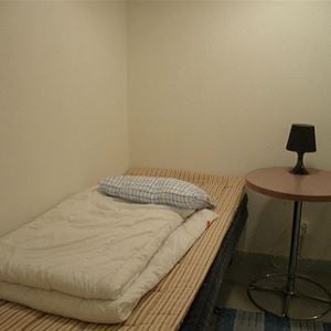 Rum med enkelsäng och ett sängbord.