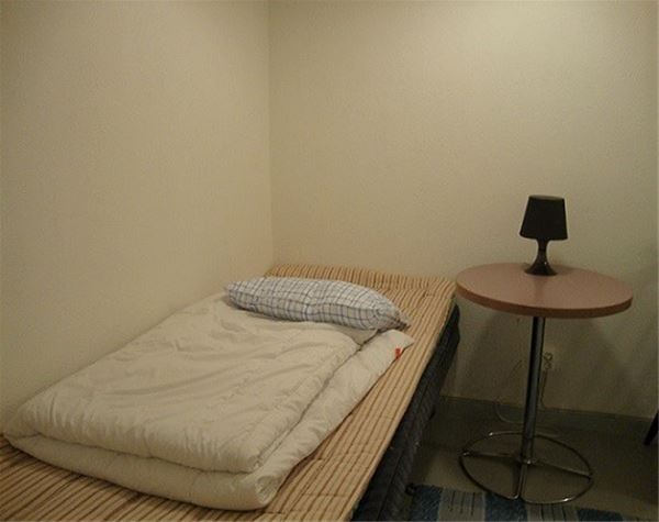 Rum med enkelsäng och ett sängbord. 