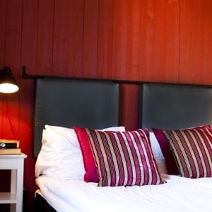 hotellrum, röd vägg, svart sänggavel, röda kuddar.