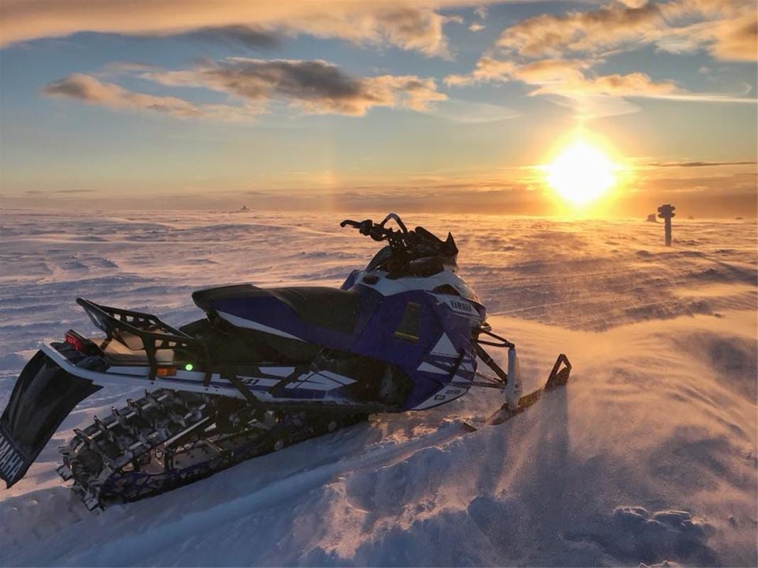 Snowmobile on mountain in sunset.