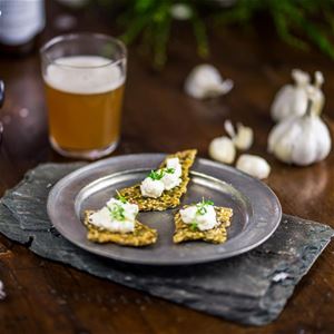 Serveringsfat med kex med kräm på, ett glas dricka.