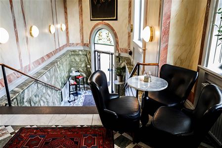 Entredörren och en trapp upp till restaurangen. Bord och stolar.