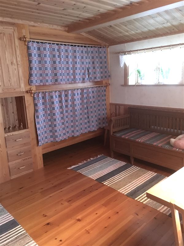 Site-built bunkbed with woven curtains and a built-in cabinet. 