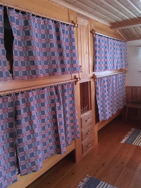 Site-built bunkbed with woven curtains and a built-in cabinet between the beds.