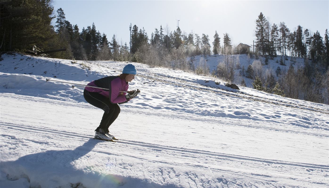 A woman cross-country skiing downhill.