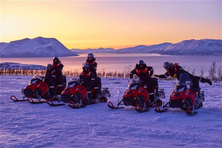 People posing on snowmobiles