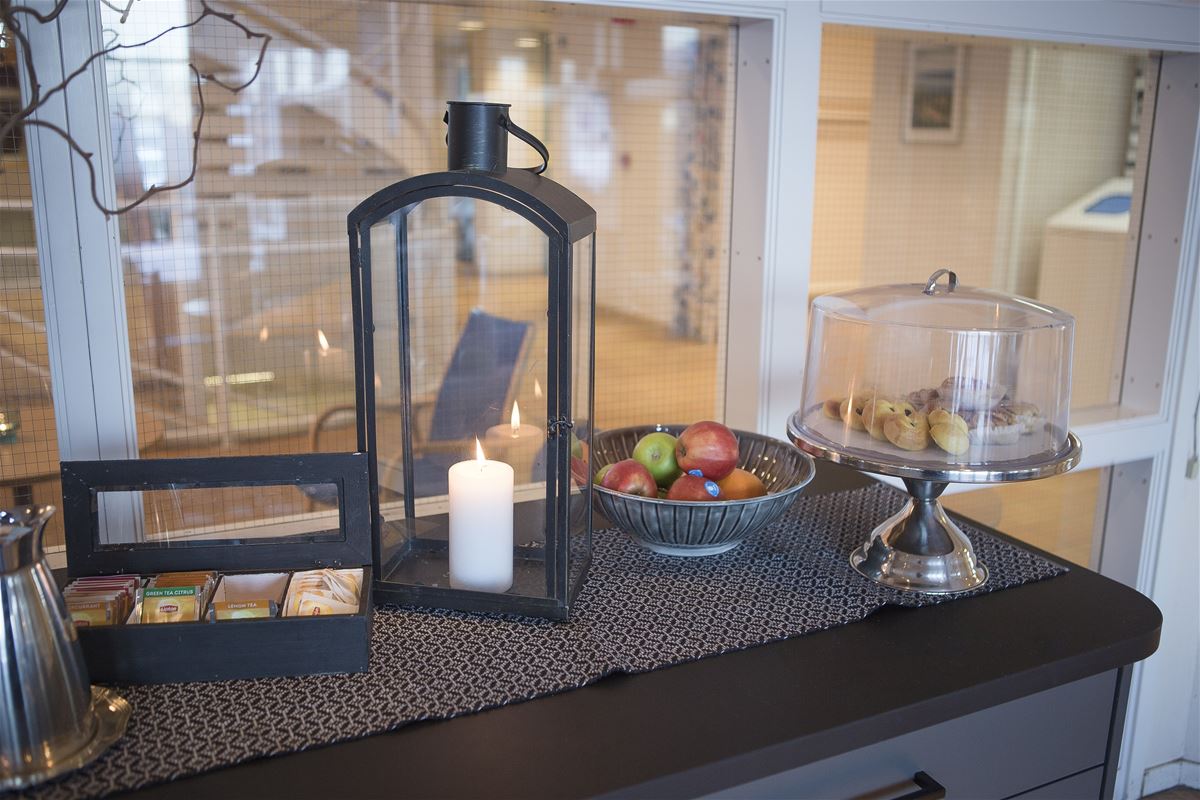 Detail of candle lantern, tea bags, plate with fruit and plate with cookies.