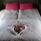 Bed with white and floral bedlinen and floral and red pillows.