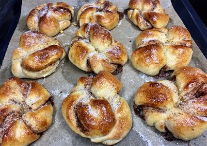 Freshly baked cinnanmon buns on a baking tray.