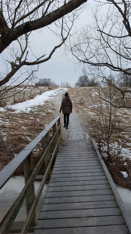 Kvinna går längs med stig vintertid.