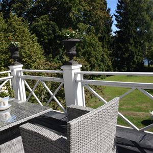 Balkong med utemöbler och utsikt över trädgården.