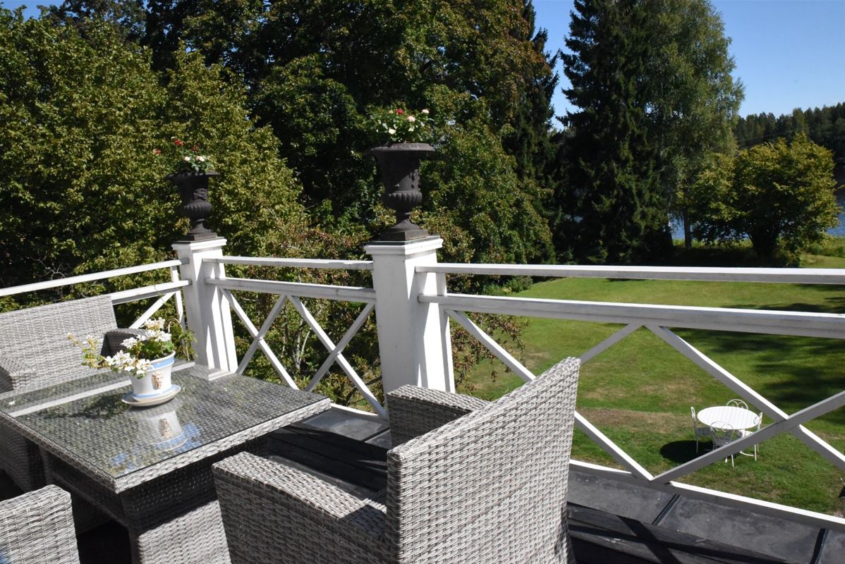 Balkong med utemöbler och utsikt över trädgården.