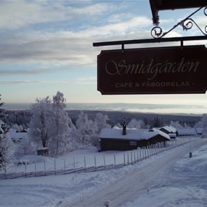 Siluett av Smidgårdens skylt mot en vintrig bakgrund från Fryksås. 