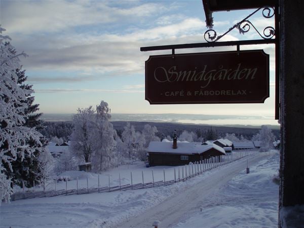 Siluett av Smidgårdens skylt mot en vintrig bakgrund från Fryksås.  